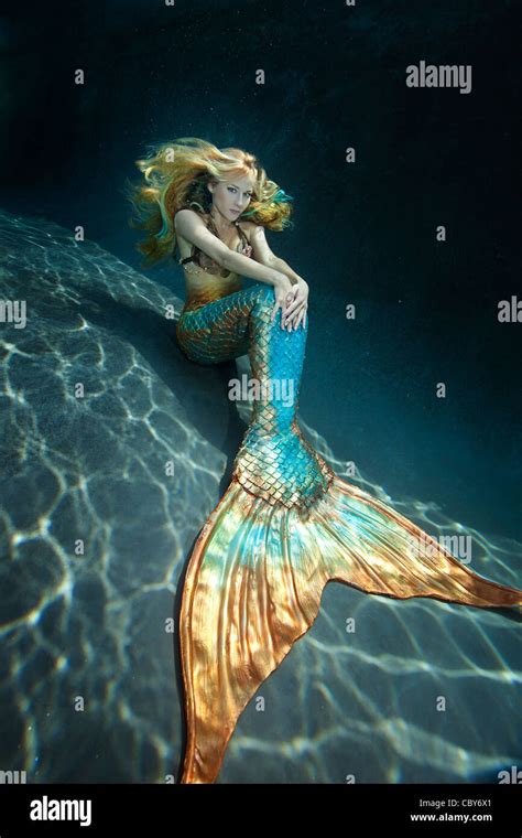Young Mermaid Sitting Underwater With Her Hands On Her Tail Stock Photo