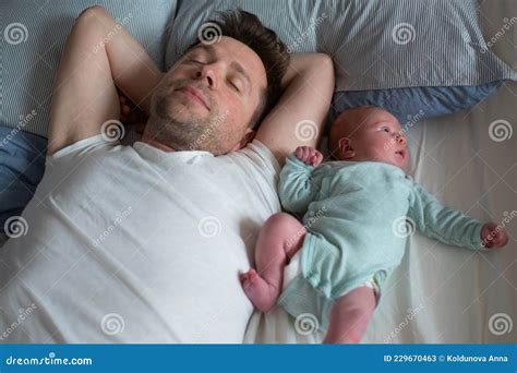 Young Caucasian Father And Baby Girl Sleeping On Bed Together Stock