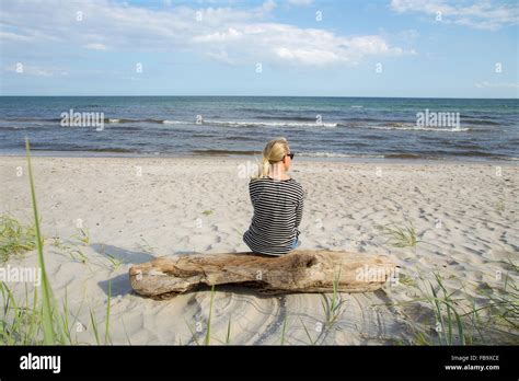 Sweden Skane Soderslatt Beddinge Mature Woman Sitting On Driftwood