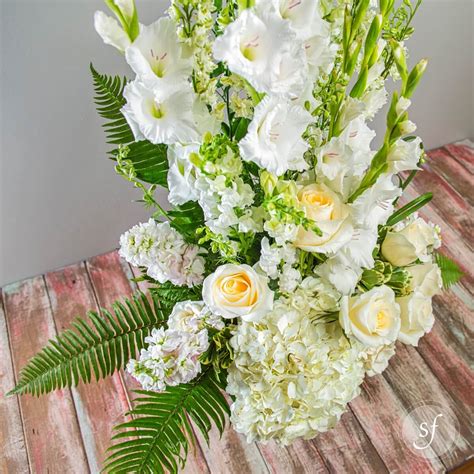 Flower decoration on transparent podium with backdrop and candles. Peaceful Urn in White - Flower Collection - Steve's Floral