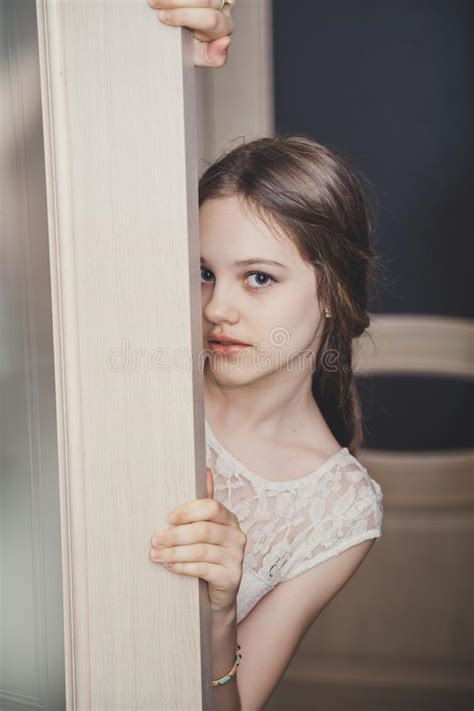 Предназначенная для подростков девушка смотря от за двери между комнатами Стоковое Изображение
