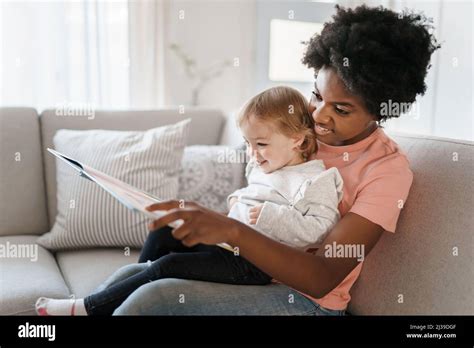 nursery babysitter with baby reading a book Stock Photo - Alamy
