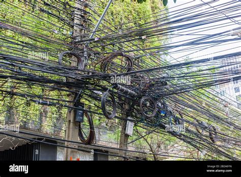 Messy And Untidy Electrical Cables Hanging From An Electricity Pole In