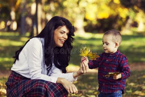 Beautiful Mother Plays With Her Son In The Park In Autumn Stock Image
