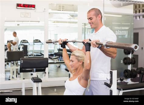 Trainer Helping Woman With Lifting Barbell In Gym Stock Photo Alamy