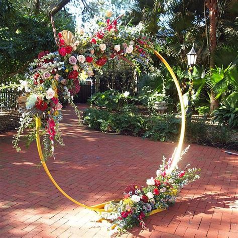 A Circular Arch Decorated With Flowers And Greenery On A Brick Walkway