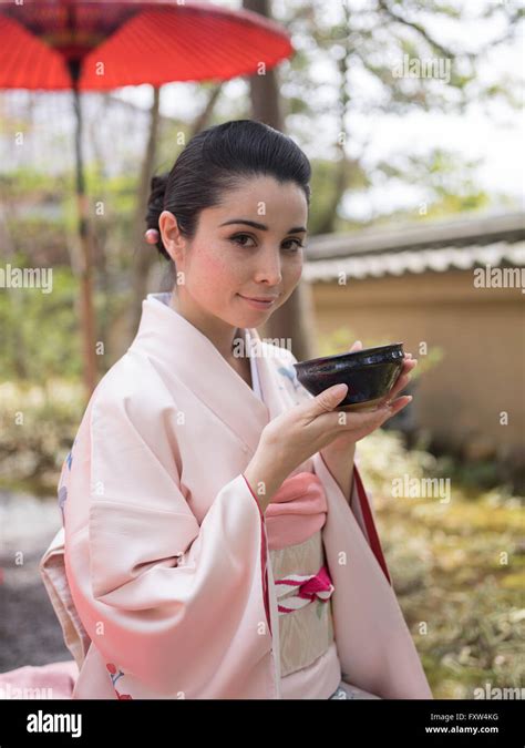 Japanese Woman In Kimono Drinking A Bowl Of Green Tea In The Gardens Of