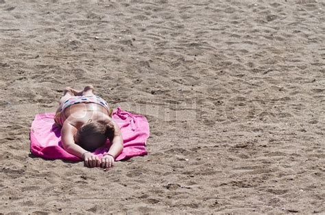 A Woman Lies On A Sandy Beach To Tan In Stock Photo Colourbox