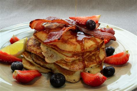Pancake Stack With Crisp Bacon Blueberries Strawberries And Maple Syrup
