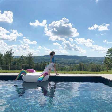 A Woman Standing On Top Of An Inflatable Unicorn Pool Float Next To A