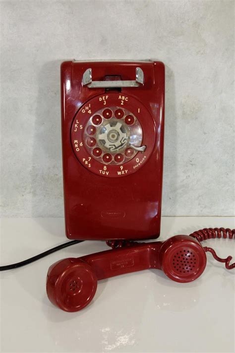 An Old Fashioned Red Phone Sitting On Top Of A White Counter Next To A