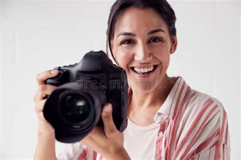 Portrait Of Smiling Female Photographer With Camera Against White