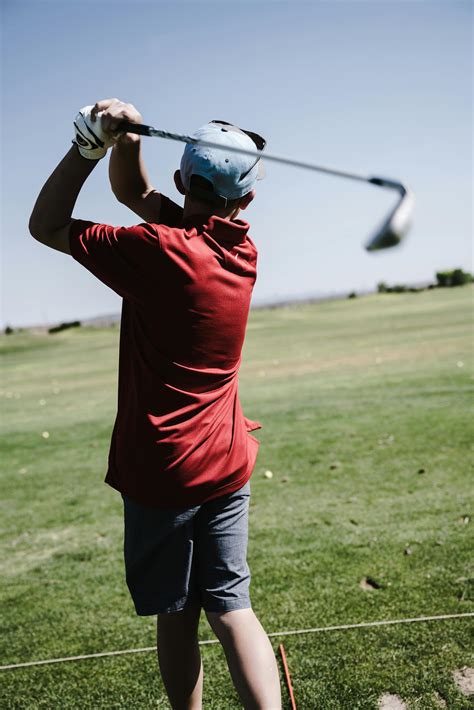 Man Swinging Golf Club Facing Grass Field · Free Stock Photo