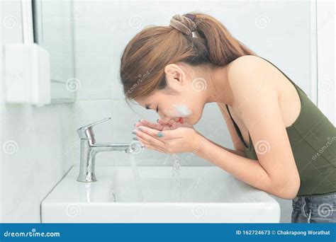 Beautiful Young Woman Washing Her Face Splashing Water In A Bathroom