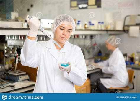 Researching In Laboratory Focused Young Female Pipetting Reagent Into