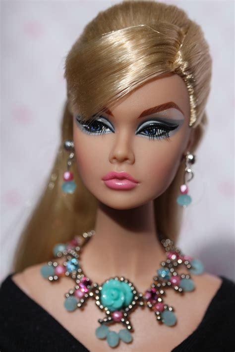 a barbie doll with blonde hair and blue eyes wearing a black dress necklace and earrings