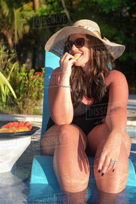 Elegant Woman Sitting In A Pool And Enjoying Food Looking At The Camera West Bay Roatan Bay
