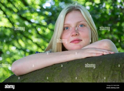 Blonde Caucasian Teenage Girl Leaning On Branch Of Tree In Nature Stock
