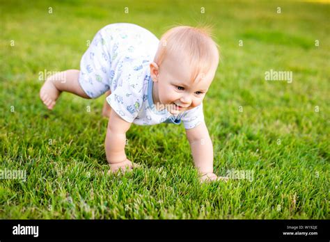 Summer Portrait Of Happy Funny Baby Boy Outdoors On Grass In Field