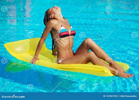 Portrait Of Beautiful Tanned Woman Relaxing In Swimming Pool In Striped