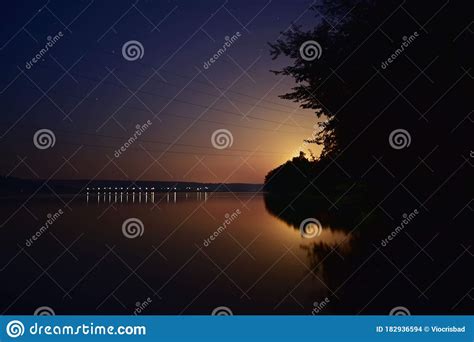 Lake At Night Reflecting Shiny Moon On Water Surface Stock Photo