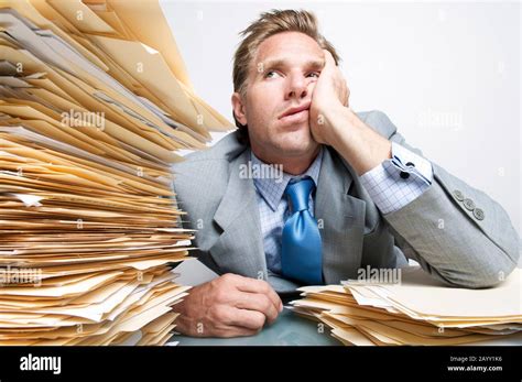 Bored Office Worker Looking Overwhelmed At The Huge Pile Of Paperwork