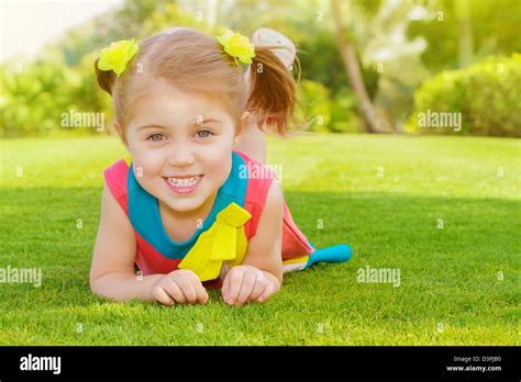 Picture Of Cute Little Girl Lying Down On Green Grass In Park Cheerful