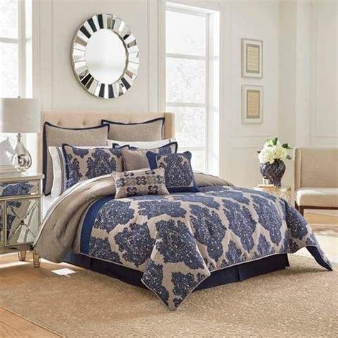 A Bed In A Bedroom With Blue And White Comforter Set On Top Of It