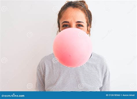Young Redhead Woman Chewing Gum And Blowing Hair Bubble Over White