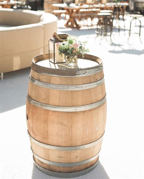A Wooden Barrel With A Wedding Cake On Top Sits In The Middle Of An