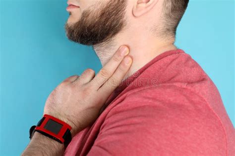 Young Man Checking Pulse On Neck Against Color Background Stock Photo