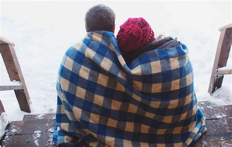 Couple Cuddled Together Under Blanket Sitting On Porch On Winter Day By Stocksy Contributor