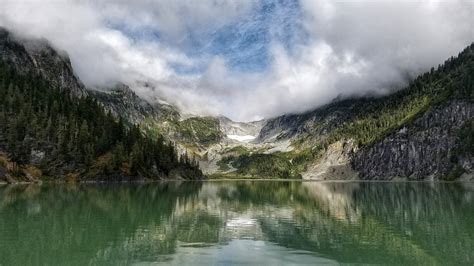 A Lake Surrounded By Mountains On A Cloudy Day Clouds Over A Lake 4k