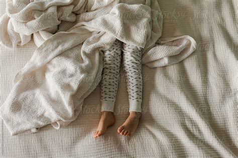 the legs of sleeping girl in bed with arrow print pajamas by stocksy contributor amanda