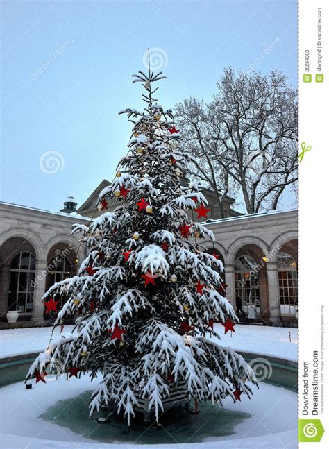 Snow Covered Christmas Tree With Ornaments Outside In Park Of German