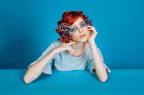 Charming redhead woman in wire eyewear in blue studio · Free Stock Photo