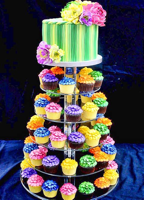 A Multi Tiered Cake With Cupcakes And Flowers On The Top Is Decorated