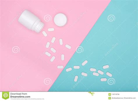 medication bottle and white pills spilled on blue and pink pastel coloured background