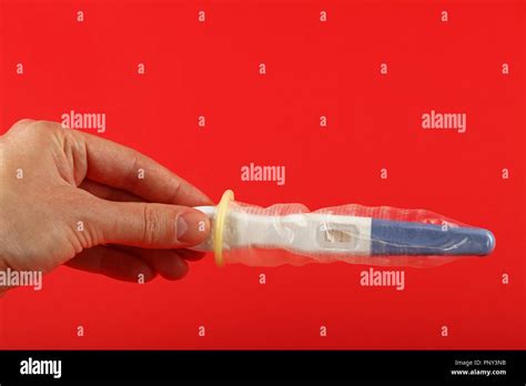 Close Up Woman Hand Holding Pregnancy Test With Condom On It Over Red Background With Copy Space