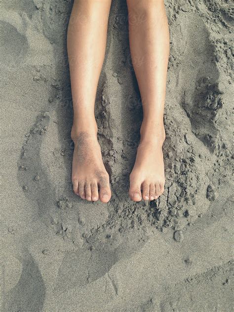 Feet Of Eleven Year Old Girl Laying On Sand At Beach Del Colaborador