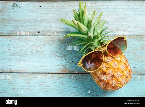 Pineapple With Sunglasses Against A Blue Wooden Background Stock Photo
