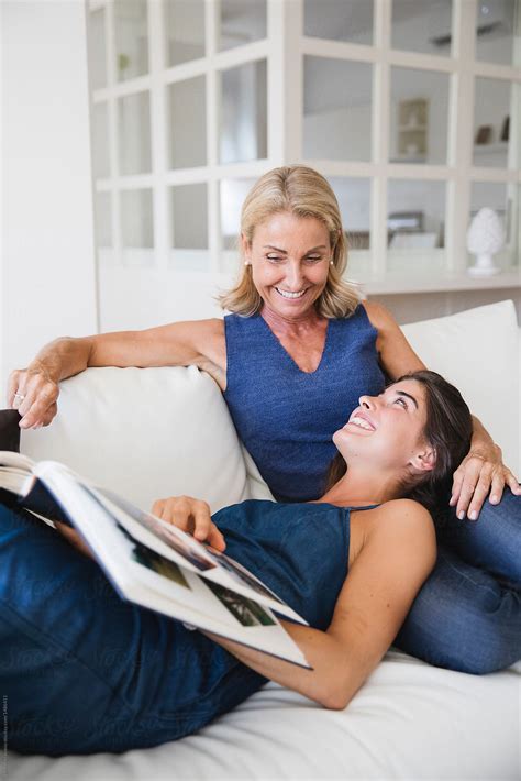 Happy Mother And Daughter Looking At A Photo Album Together On The Sofa By Stocksy Contributor