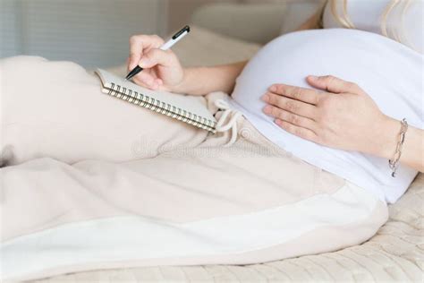 Young Pregnant Woman Packing Suitcase For Maternity Hospital At Home