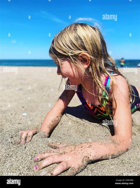 Junge Blonde Mädchen Spielen Im Sand Am Strand Im Sommer Lachen Und Spaß Haben Stockfotografie