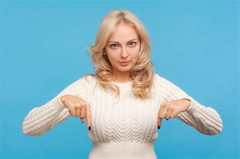 Premium Photo Confident Bossy Blond Woman In White Knitted Sweater Pointing Fingers Down
