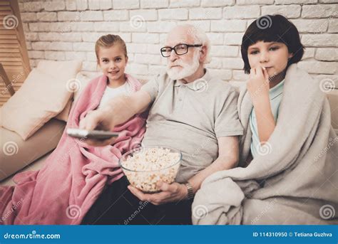 Avô Neto E Neta Em Casa O Vovô E As Crianças Estão Olhando O Filme Na Tevê E Estão Comendo A