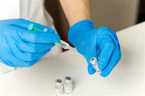 Doctor Hands Injecting A Syringe Needle Into A Small Bottle With A