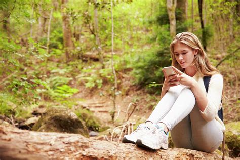 Teenage Girl Sitting Alone In A Forest Using A Smartphone