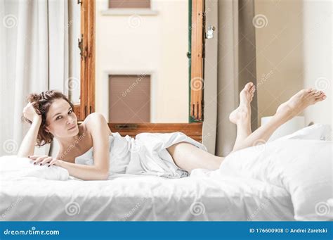 Charming Girl Lies In Bed She Stretched Out Her Legs And Looks