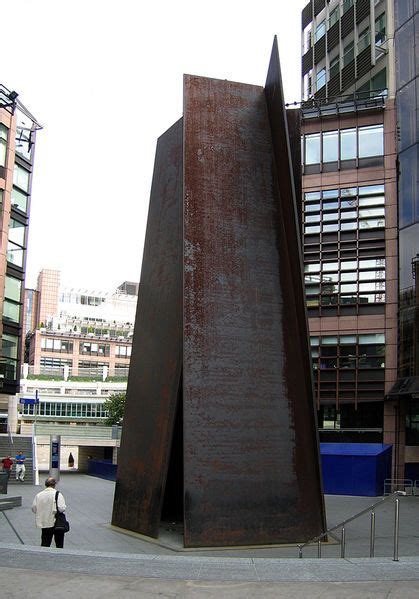 A Tall Metal Object Sitting In The Middle Of A Street Next To Some